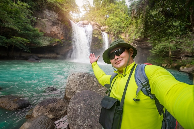 Tourists carry backpack, take photos and selfie at traveling ecotourism. Tourist trekking to see amazing of Haew Suwat Waterfall. Unseen Khao Yai National Park, Thailand, UNESCO World Heritage Area