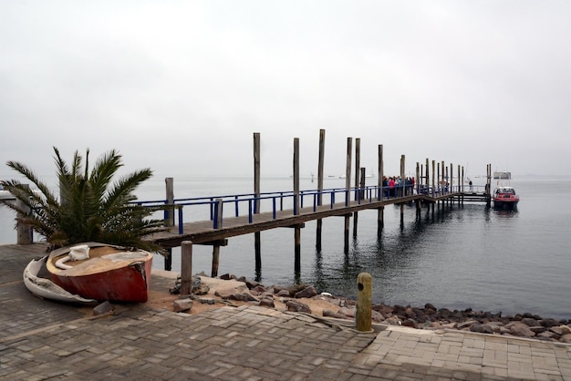 Photo tourists disembark from a pleasure boat on a wooden sea pier after a walk on the sea