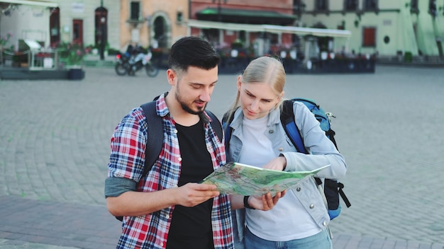 Tourists holding map and looking for some place on city square. They going sightseeing.