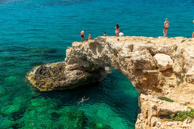 Tourists jump from a height into the azure waters of the Mediterranean Sea.