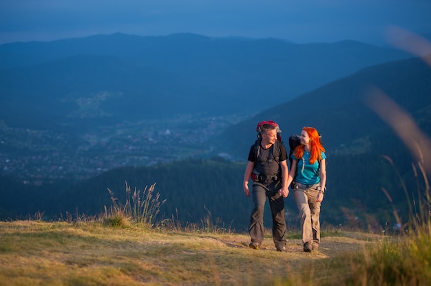 Туристы мужчина и женщина с рюкзаками гуляя в красивейшие горы