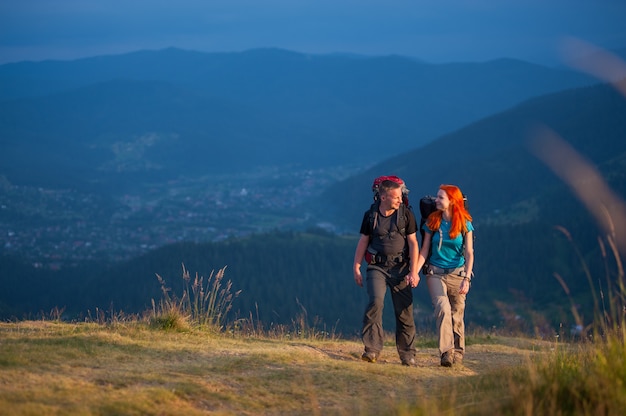 Tourists man and woman with backpacks walking in the beautiful mountains area