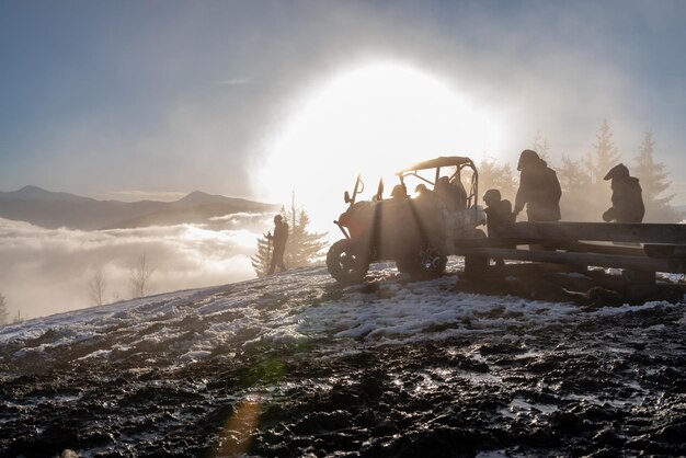 Tourists and motorcycle tourists on top of a mountain with an atv contours and outlines of people