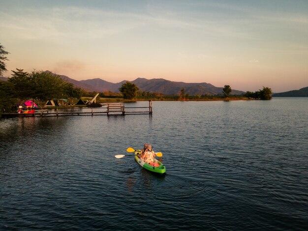 Tourists paddling in canoe on the lake and sunset over mountain view