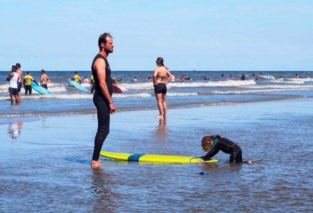 Photo tourists and people on holiday as well as a surfer in the north sea on scheveningen beach