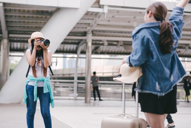 Foto turisti che fotografano un amico in piedi sul marciapiede in città