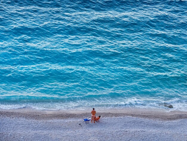 Tourists relax on the beach of the turquoise ionian sea in greece