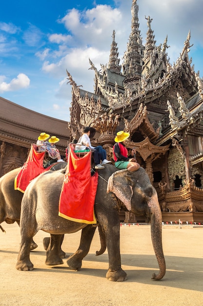 Tourists ride elephant around the Sanctuary of Truth in Pattaya