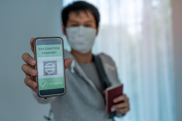 COVID19 の予防接種を受けたパスポート申請書を見せる観光客 携帯電話に予防接種証明書を持っている 国際証明書は出張や観光で受け入れられます