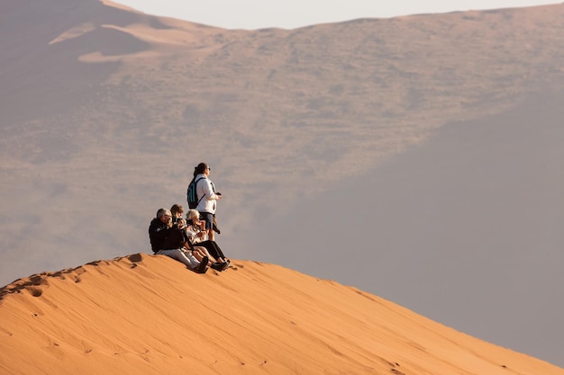 I turisti si siedono sulla sabbia in cima a una duna a sossusvlei, namibia, africa.