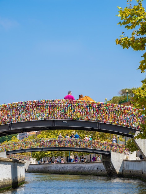 Tourists taking photos and looking at the canal from the arched bridge full of colored strips