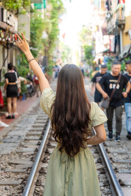 Туристы фотографируют мчащийся поезд. Железнодорожная улица Ханоя – популярная достопримечательность. Вид на поезд, проходящий по узкой улочке Старого квартала Ханоя.