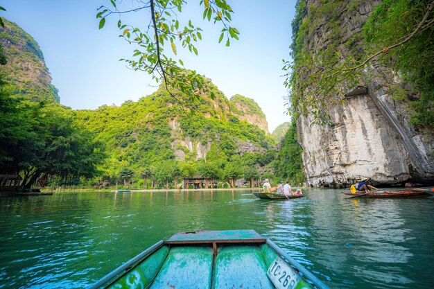 사진 코크 (tam kok) 강을 따라 항해하는 관광객들, 베트남 닌빈 (ninh binh) 지방, 오를을 기 위해 발을 이용하는 오르기 선수들, 카르스트 탑과  으로 형성된 풍경