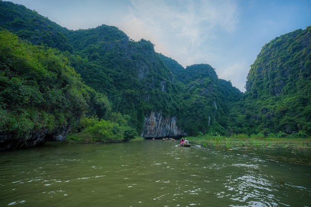 사진 코크 (tam kok) 강을 따라 항해하는 관광객들, 베트남 닌빈 (ninh binh) 지방, 오를을 기 위해 발을 이용하는 오르기 선수들, 카르스트 탑과  으로 형성된 풍경