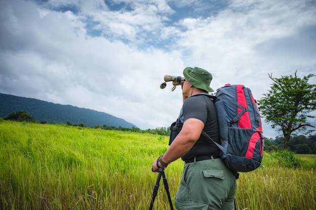 Tourists use binoculars to see birds and wildlife in the grasslands in the tropical forest. Khao Yai National Park, Thailand. Bird, hornbill and monkey tours. Ecotourism concept photo.