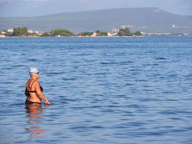 Tourists and vacationers swim in the Aegean sea and relax on the beach on a summer day in Greece