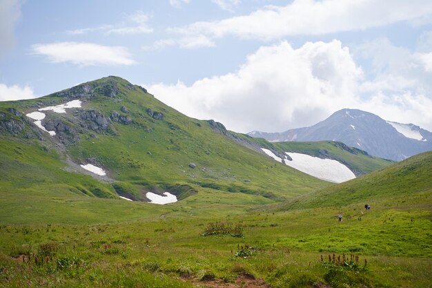 Foto i turisti camminano lungo un percorso di montagna attraverso una valle verde