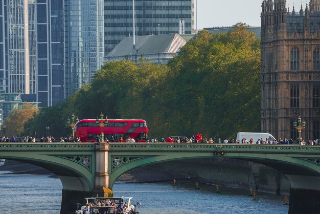 Photo tourists walking by tour bus on famous westminster bridge towards palace