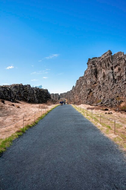 Foto turisti che camminano sulla strada tra le scogliere contro il cielo nel parco nazionale di thingvellir