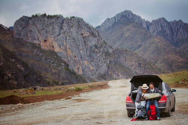 Туристы с картой и рюкзаками в машине в горах