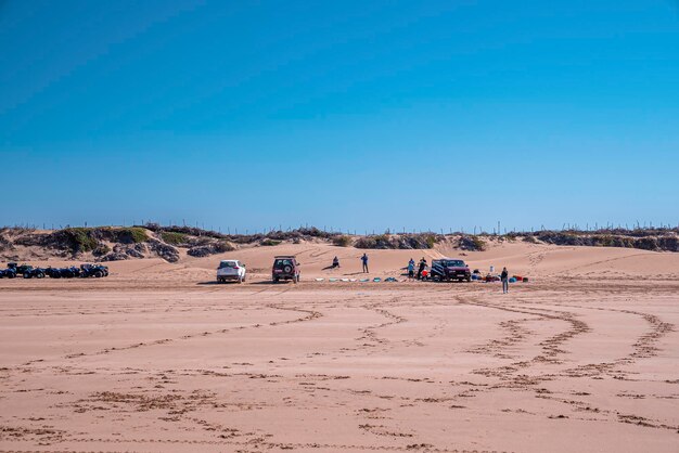 Photo tourists with quadbikes cars and surfboards on sand