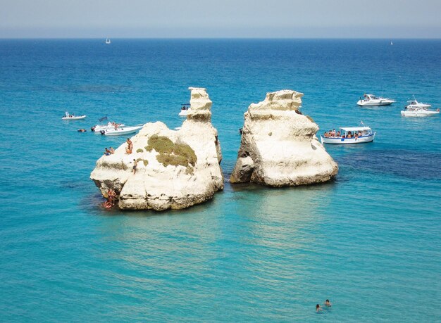 Foto turisti e yacht vicino a formazioni rocciose in mare