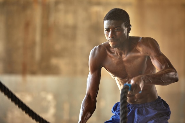 Touwtraining sportman doet gevechtstouwen oefenen buiten zwarte mannelijke atleet oefent functionele fitnesstraining met zwaar touw