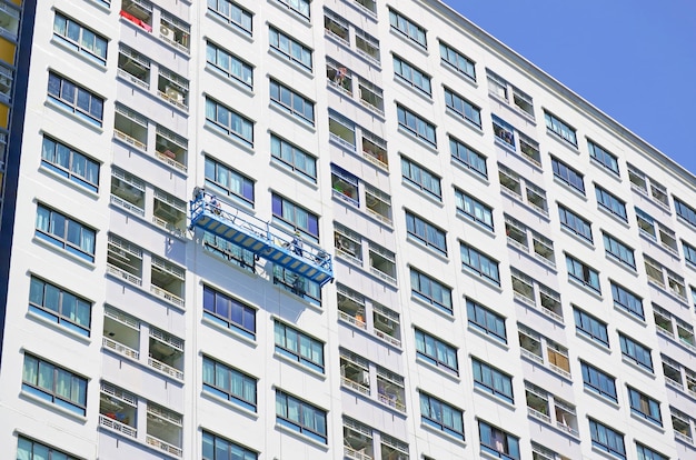 Touwwerkers schilderen de gevel van een hoog modern gebouw