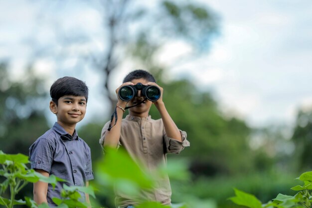 Tow kleine Indiase jongen geniet in de natuur met een verrekijker