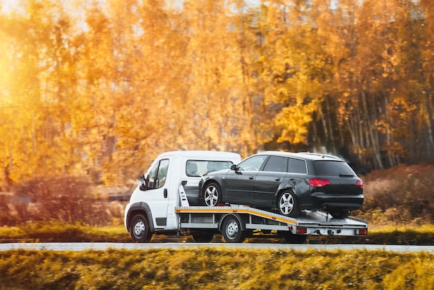 Tow truck and car on the road A vehicle breakdown and collision leads to a tow truck delivery and insurance service Roadside assistance for a car accident