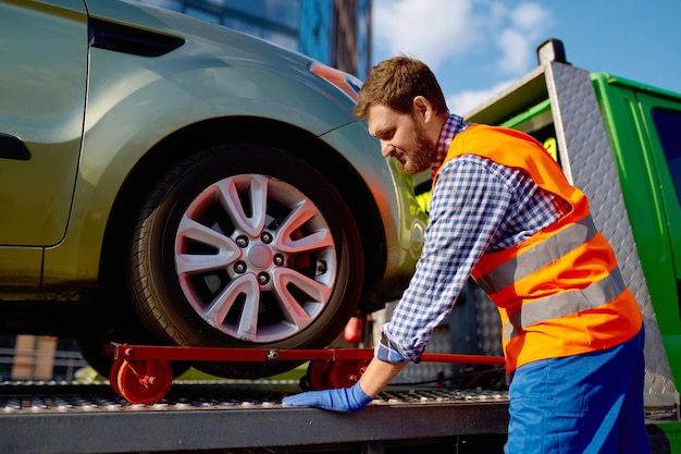 Operatore del carro attrezzi che ripara l'auto sulla piattaforma. lavoratore che si occupa di veicolo in panne