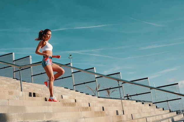 より健康的なライフスタイルに向けて。屋外で運動しながら走っているスポーツウェアの美しい若い女性の全長