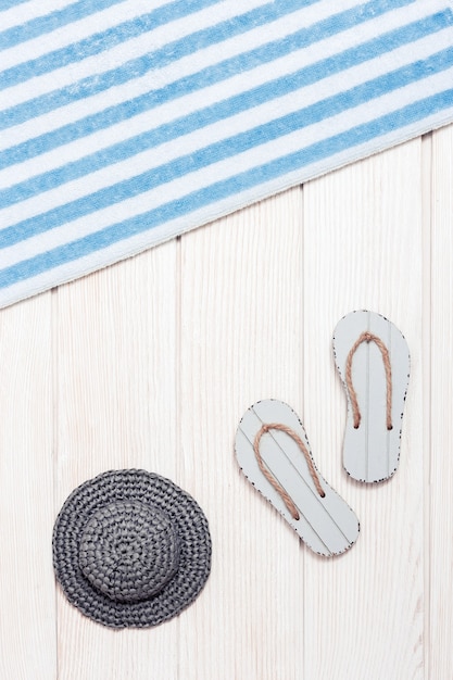 Towel and beach slippers, hat from sun on white wood, summer background.  Vacation by sea.