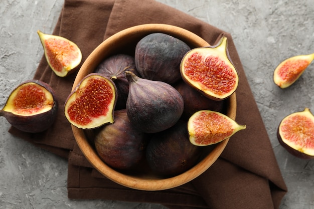 Towel and bowl with fig on gray, top view