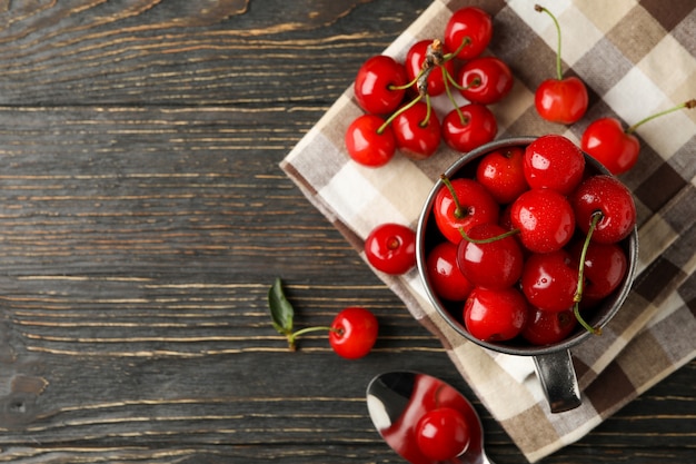 Towel and metal mug with cherry on wooden background