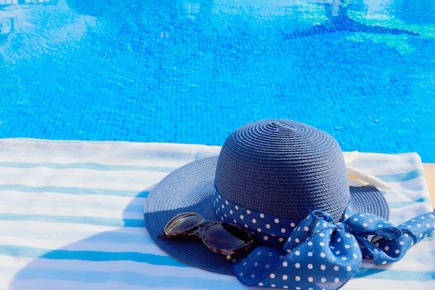 Towel and summer hat near blue clear water of pool