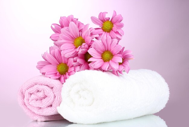 Towels and beautiful flowers on pink background