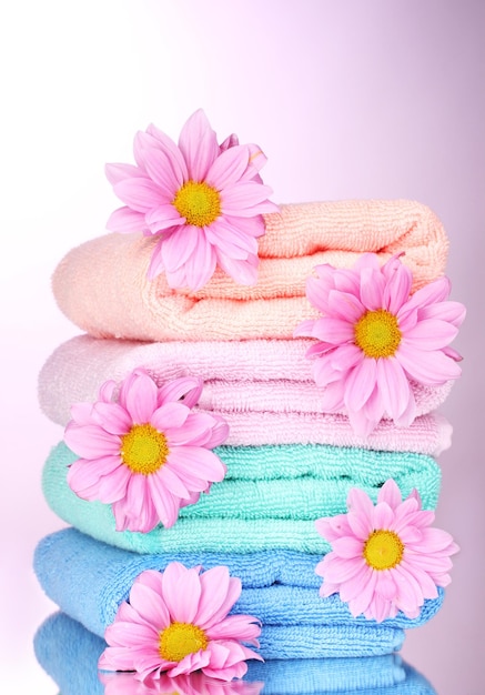 Towels and beautiful flowers on pink background