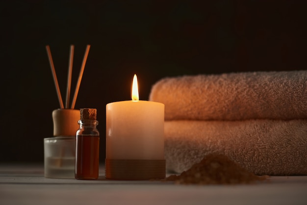 Towels, candle and massage oil on white table