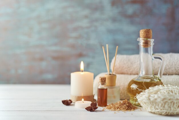 Towels, candle and massage oil on white table