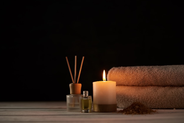 Towels, candle and massage oil on white table