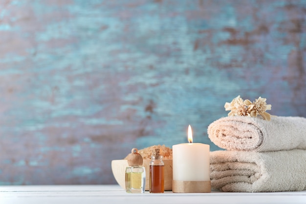 Towels, candle and massage oil on white table