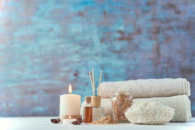 Towels, candle and massage oil on white table