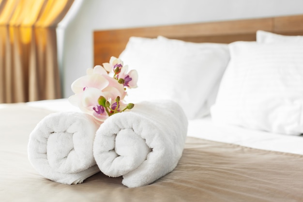 Towels and flower on bed in hotel room