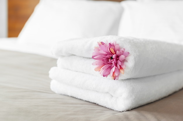 Towels and flower on bed in hotel room