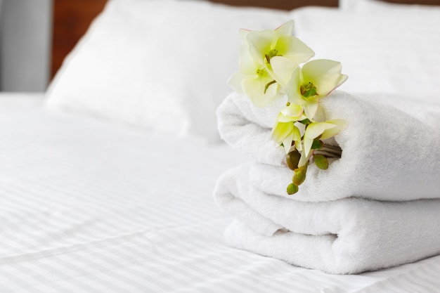 Towels and flower on bed in hotel room