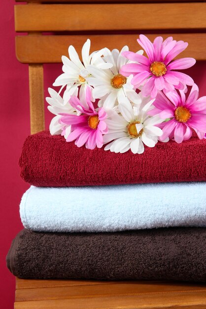 Towels and flowers on wooden chair on brown background