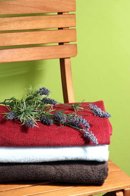 Towels and flowers on wooden chair on green background