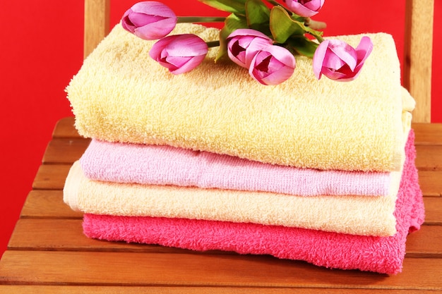 Towels and flowers on wooden chair on red surface