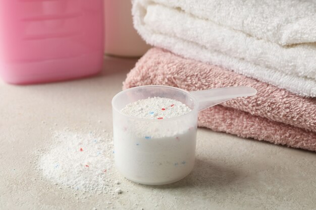 Towels, laundry liquid and scoop with powder, close up